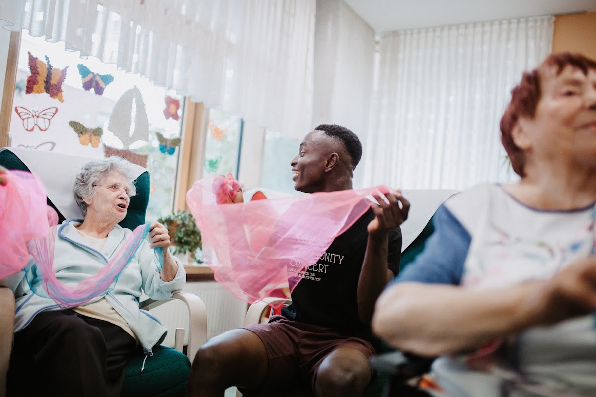 Adetayo and care-home residents waving scarves during a music session
